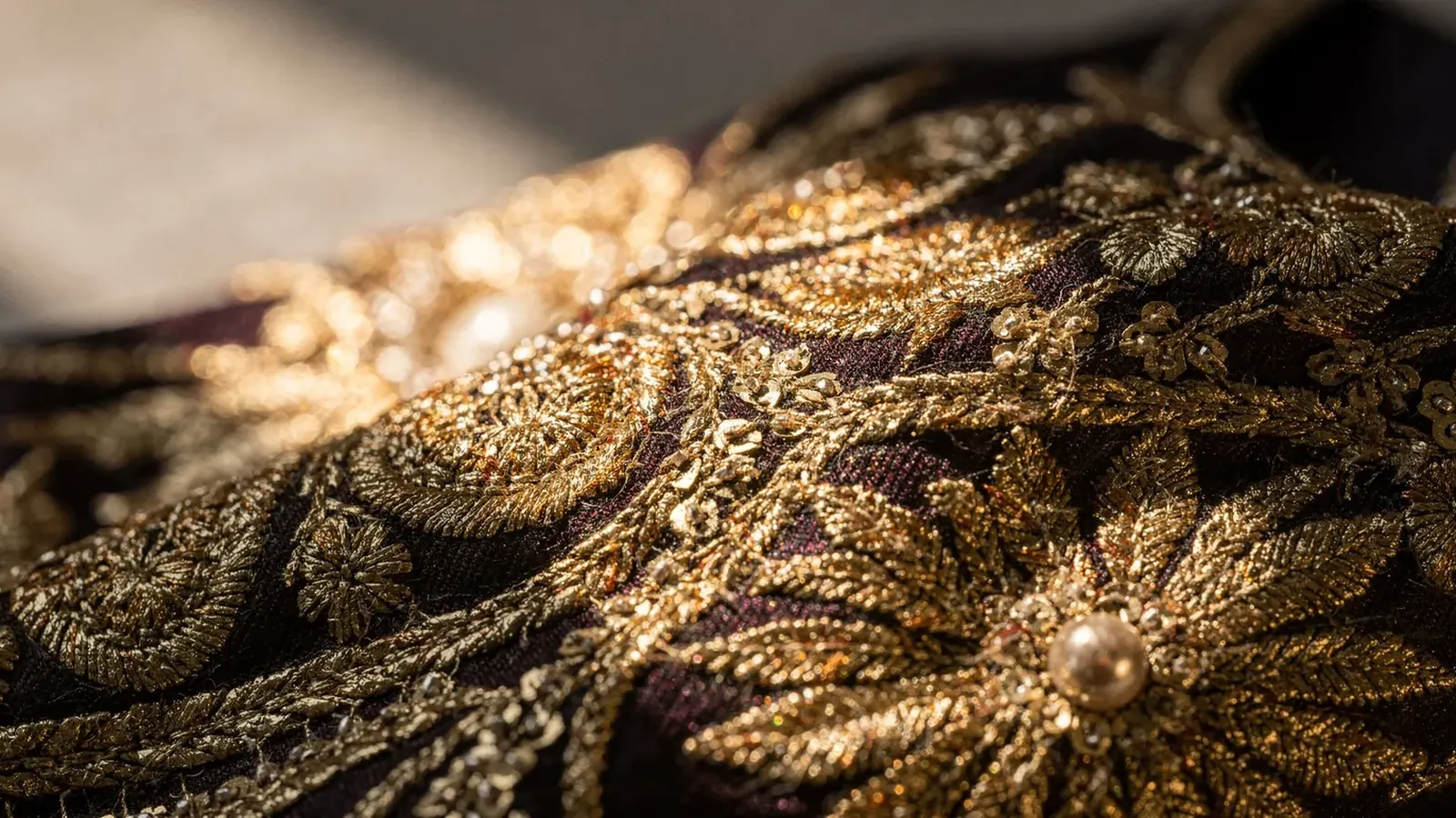 Macro detail of gold zardozi embroidery on silk